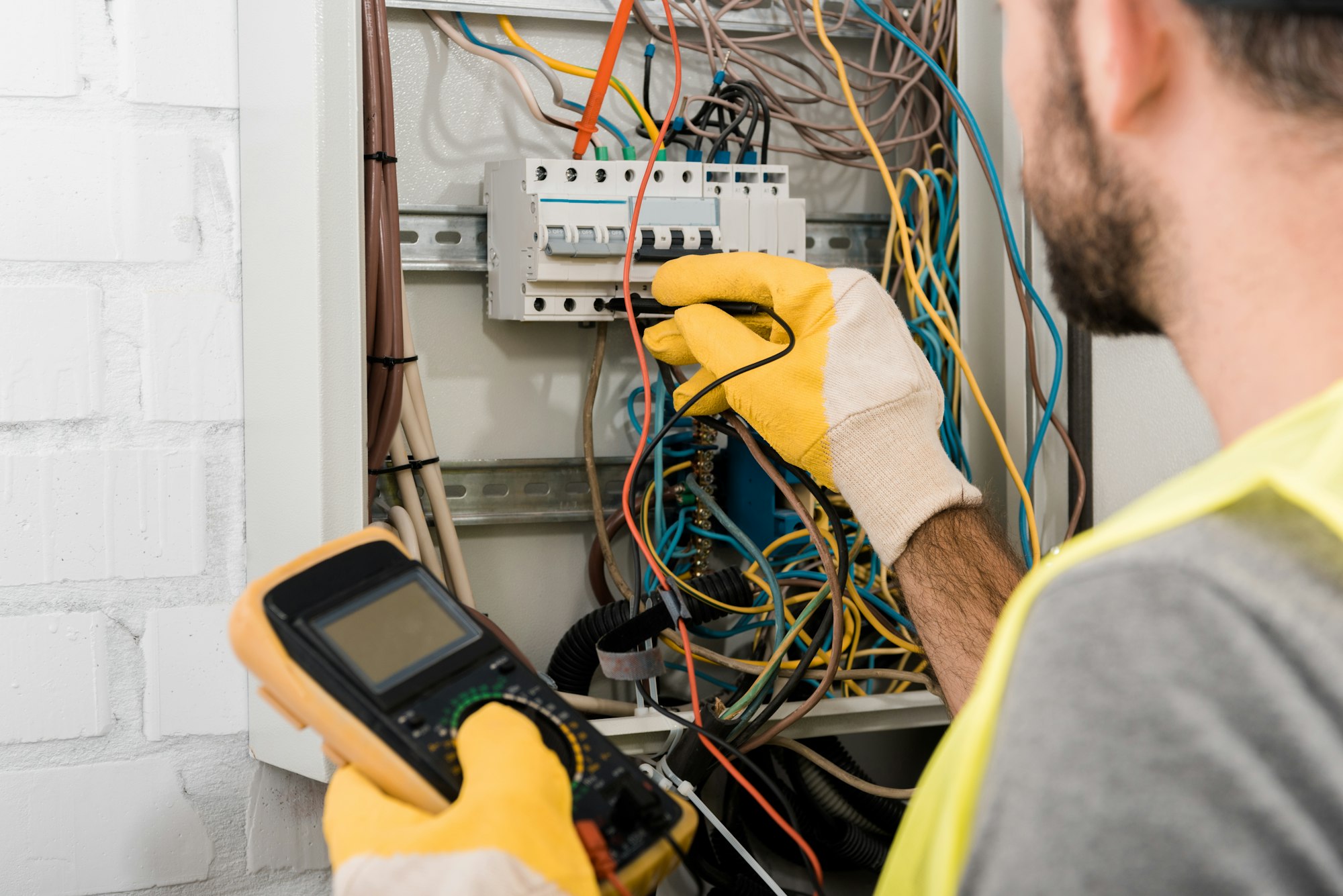 cropped image of electrician checking electrical box with multimetr in corridor